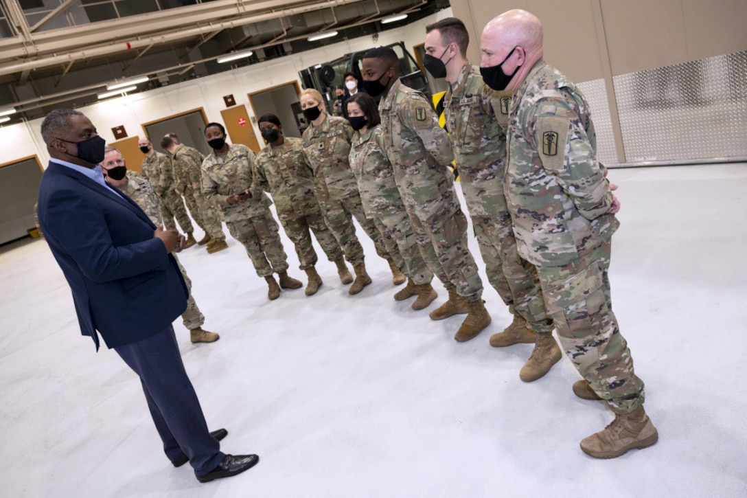 Man in business attire thanks people in military uniforms.