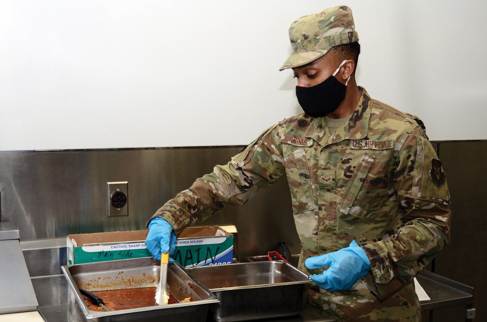 Airman 1st Class Kurt Jones, 445th FSS services apprentice, transfers an entree to a smaller pan for proper storage after the lunch period at Pitsenbarger Dining Facility, Feb. 6, 2021. Services Airmen working in the dining facility wrap leftover food and ensure the food is stored at safe temperatures for use in other meal times.