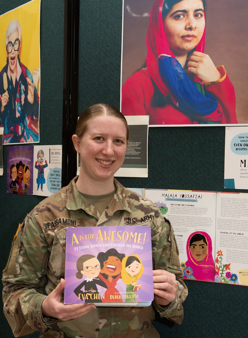 Chief Warrant Officer 2 Megan Passamoni poses in front of a display of Malala Yousafzai in the Green Mountain Armory at Camp Johnson, Vermont, March 18, 2021. Passamoni, a human resources technician with the Vermont Army National Guard's Headquarters Company, 86th Infantry Brigade Combat Team (Mountain), was one of several Guardswomen who facilitated a book reading and display of Guard uniforms and equipment for a local day care center. (U.S. Army National Guard photo by Don Branum)