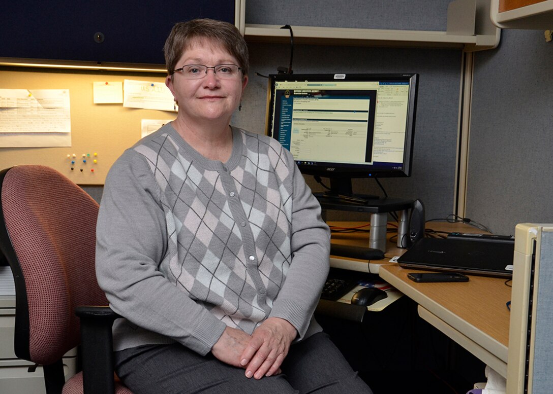 A woman poses at her desk.