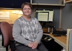 A woman poses at her desk.