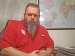 A man poses at his desk.