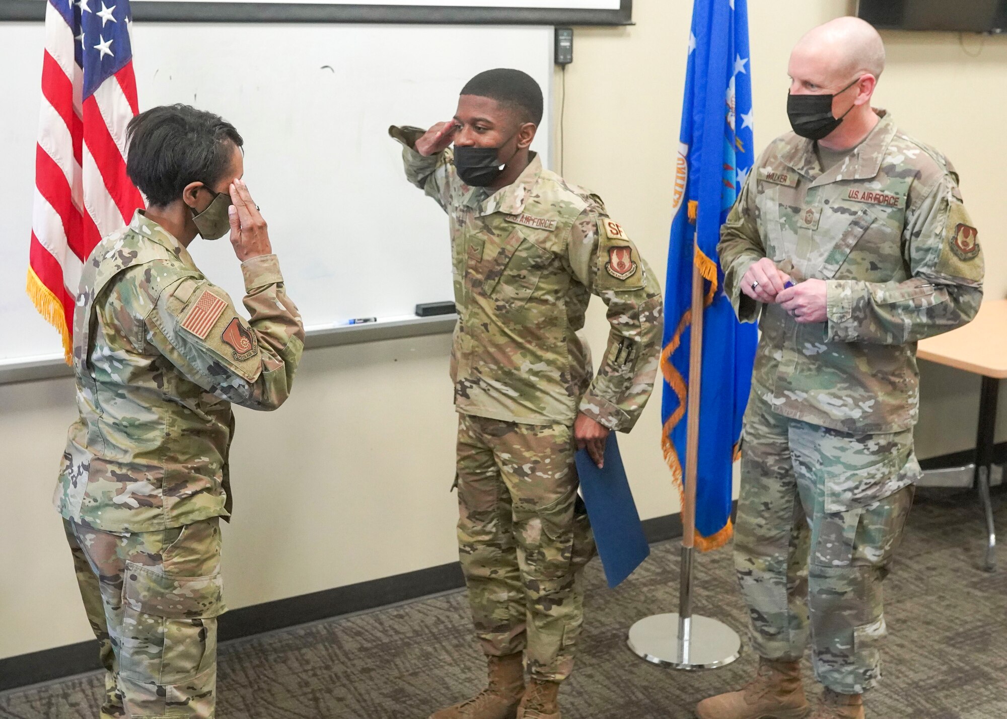 Airman First Class Kamari Johnson, a defender with the 75th Security Forces Squadron, salutes Col. Jenise Carroll, 75th Air Base Wing commander, after receiving his acceptance letter to the U.S. Air Force Academy Preparatory School as Chief Master Sgt. Christopher Walker, 75th ABW command chief, looks on March 18, 2021,