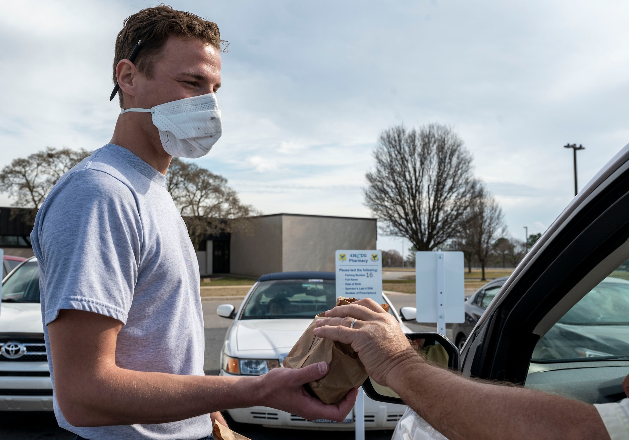 Airman 1st Class Nicholas Laurent, 9th Airlift Squadron loadmaster, delivers medication to a patient in the 436th Medical Group parking lot as part of the Park N’ Pickup system at Dover Air Force Base, Delaware, March 12, 2021. The Park N’ Pickup system was established to deliver medications to patients while ensuring the safety of both patients and workers by limiting contact. (U.S. Air Force photo by Airman 1st Class Cydney Lee)