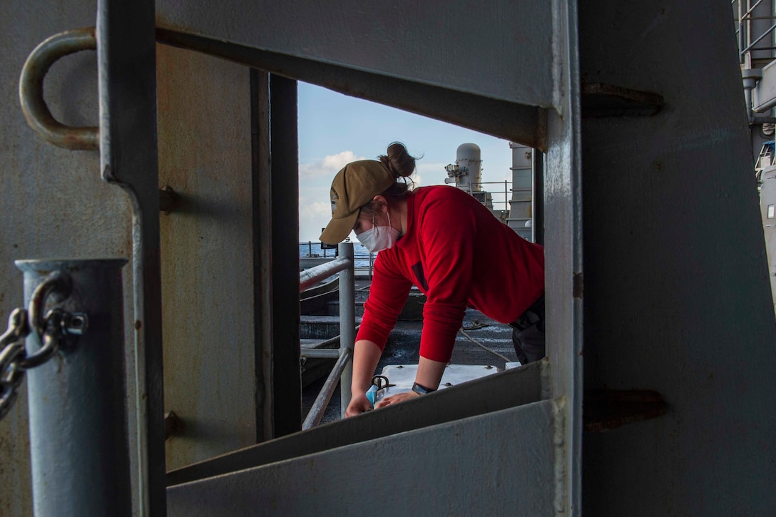 A sailor cleans a locker on board a ship.