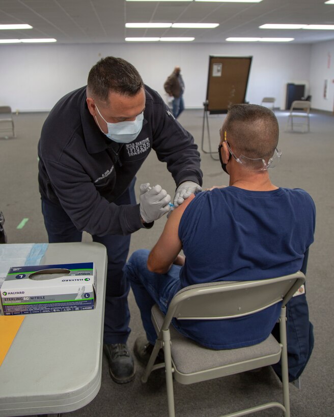 Kenneth Lyon, firefighter paramedic with Fire and Emergency Services, administers the first dose of Moderna COVID-19 vaccine to base personnel at Production Plant Barstow, Marine Depot Maintenance Command on the Yermo Annex aboard Marine Corps Logistics Base Barstow, California, March 3. The Moderna version of the vaccine requires two doses, 28 days apart. The first dose offers over 60 percent immunity and introduces the immune system to the outer shell of the virus and typically has little to no side effects other than a sore arm. The second dose is a heavier priming of the immune system as the immune system recognizes the outer shell of the virus faster and provides a robust response and over 90 percent immunity. Some recipients report exhaustion, fever and body aches for a couple of days after the second dose, which is normal.