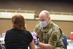 Army combat medic administers a coronavirus vaccine.