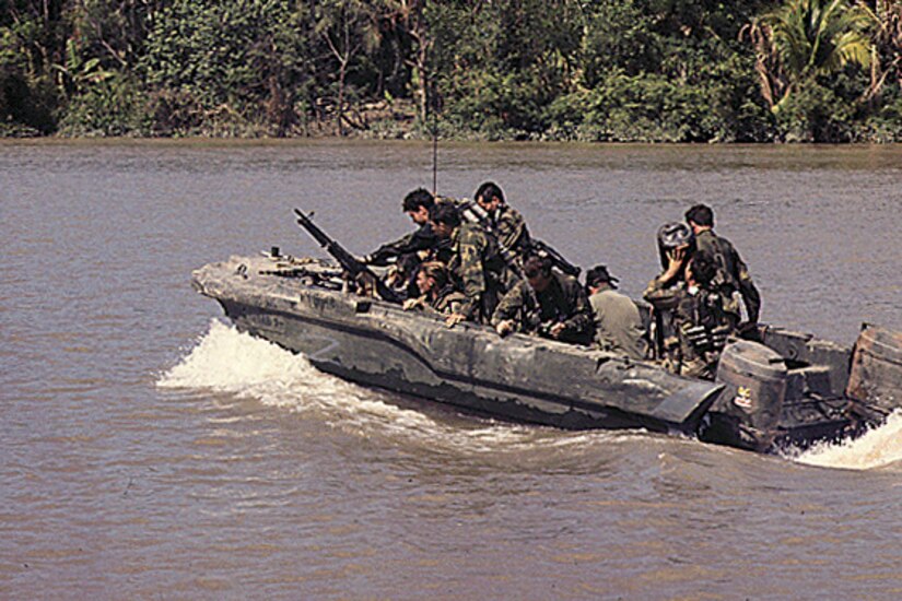 Sailors travel in a small boat on a river.
