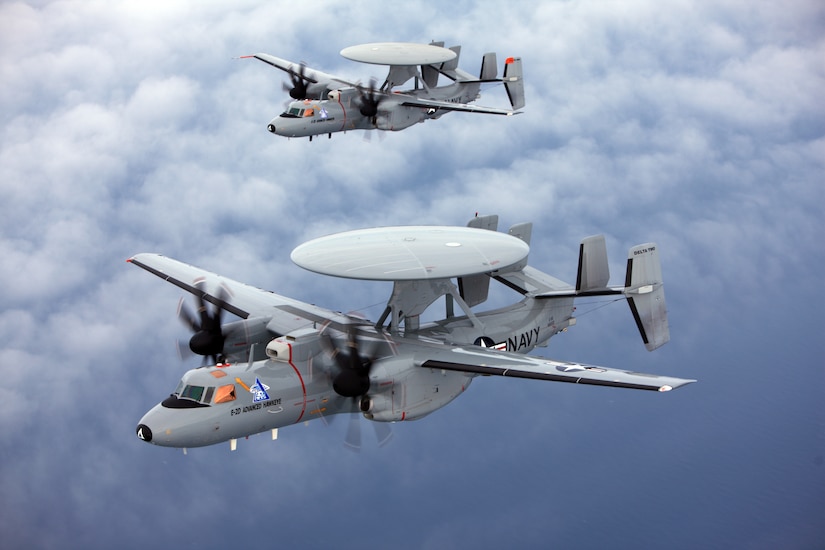 Two aircraft fly near each other in a blue sky. Each aircraft has a large, disc-shaped sensor on top.