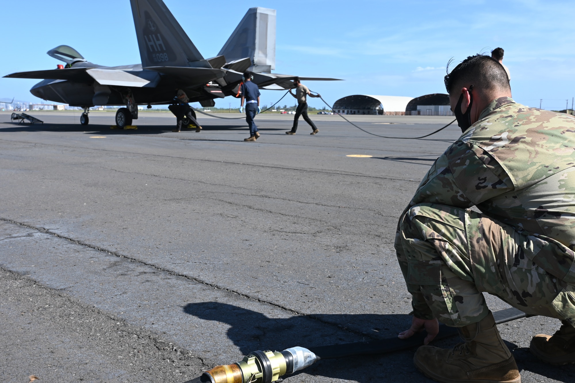 Tech Sgt. Robert Rabacal, 154th Aircraft Maintenance Squadron F-22 maintenance technician holds down a refueling hose while fellow Airmen position it towards an F-22 Raptor, Feb. 25, 2021, Joint Base Pearl Harbor-Hickam.