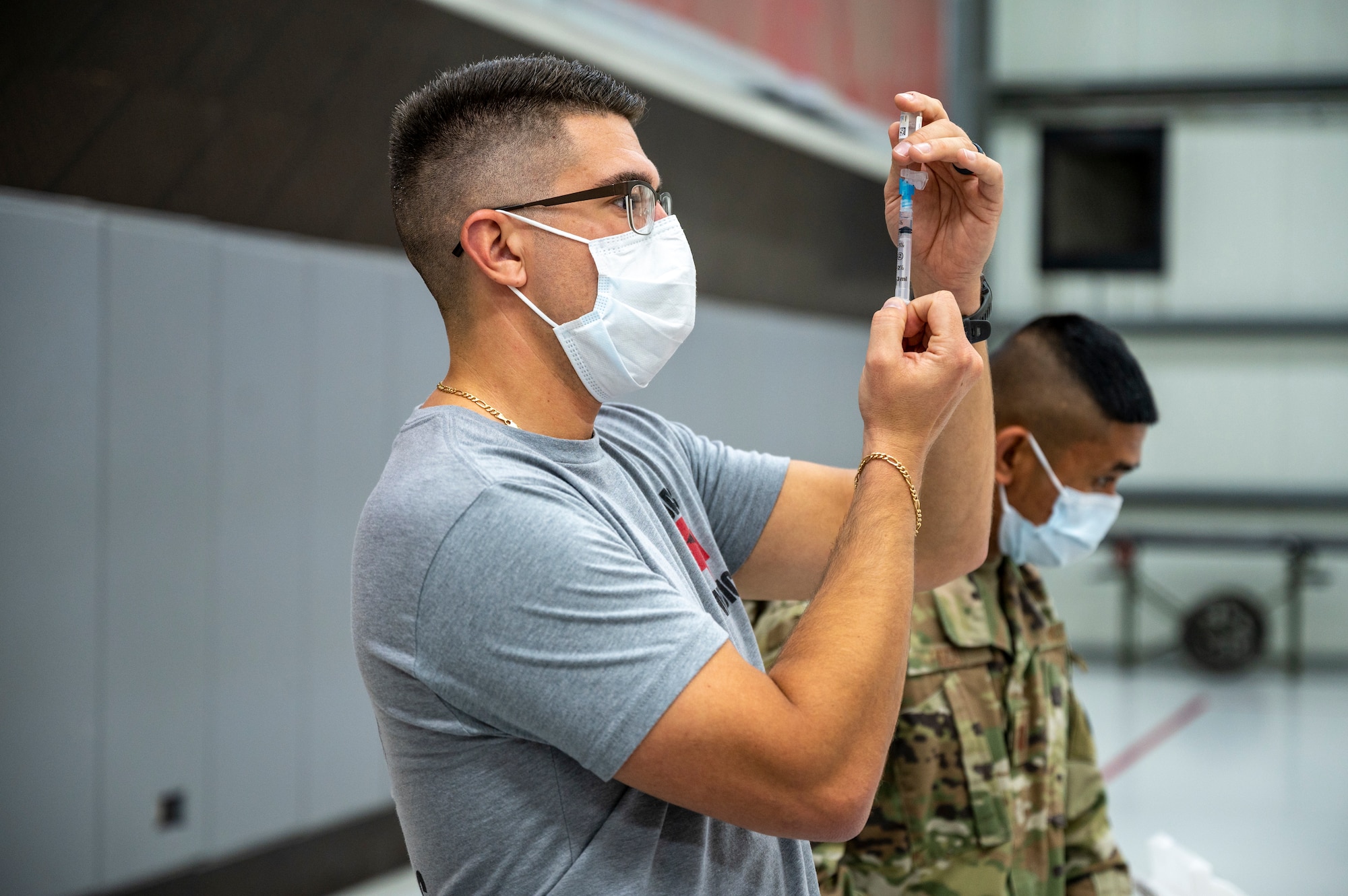 Master Sgt. Daniel Delacey prepares a syringe of COVID-19 vaccine