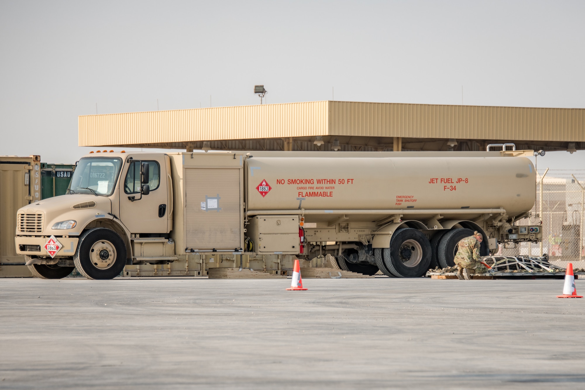 a refueling truck sits next to cargo being inspected by an Airman