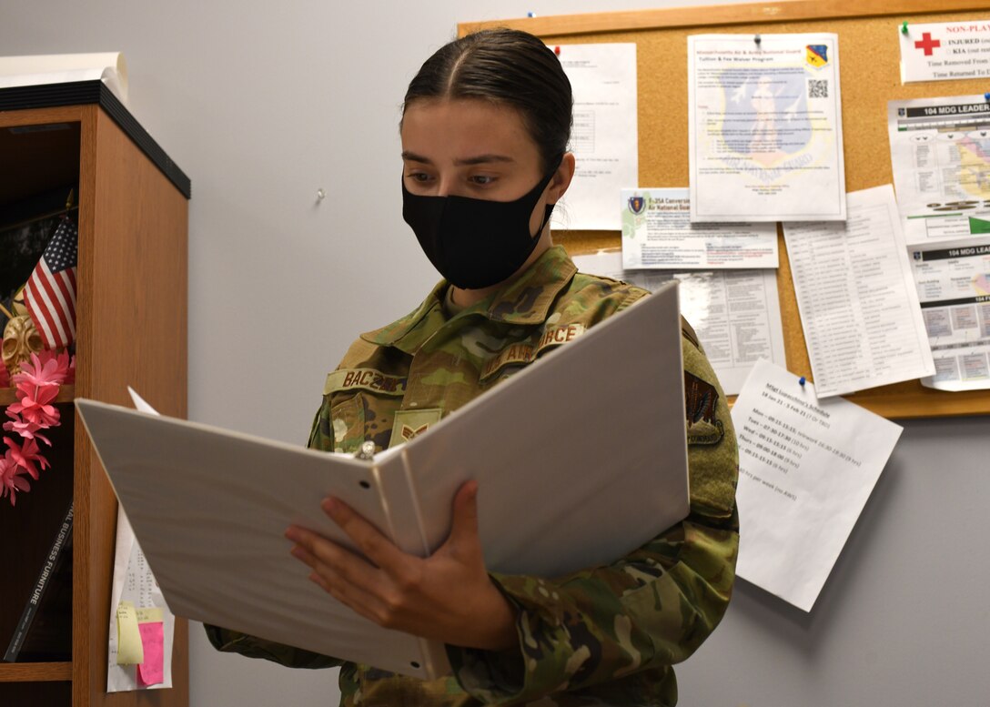 Senior Airman Weronika Baczek, a public health technician with the 104th Medical Group, views a binder, in her office at Barnes Air National Guard Base, Massachusetts, Feb. 17, 2021. Contact tracing is critical for safeguarding 104th Fighter Wing mission readiness and the health of our Barnestormers and surrounding communities from COVID-19. (U.S. Air National Guard courtesy photo)