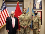 Three people standing in front of an American flag.