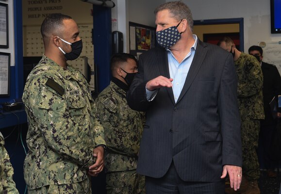 The Honorable James F. Geurts, currently performing the duties of Under Secretary of the Navy, engages with Aviation Electronics Technician 3rd Class Zackery Brannan, a Sailor assigned to Strike Fighter Squadron (VFA) 106.