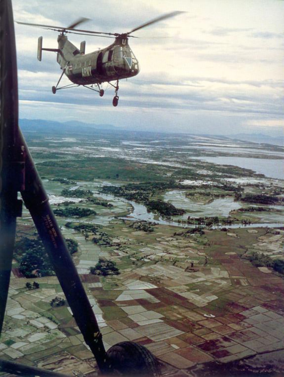 Helicopters fly above fields and bodies of water.