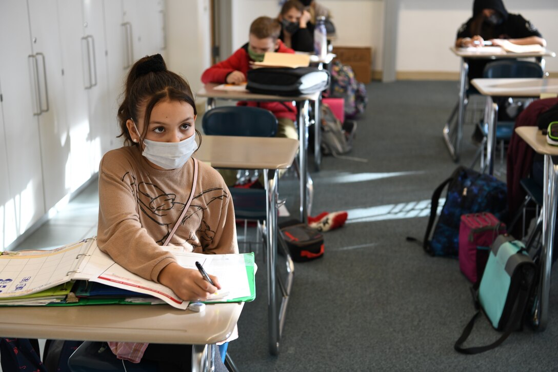 Young students sit and take notes in a classroom.