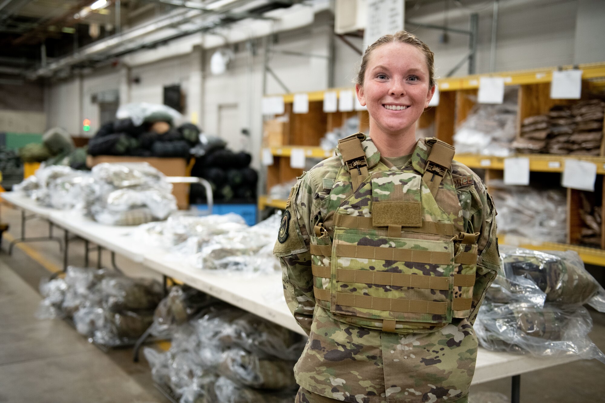 Airman Grace Bailey poses in front of the Aspetto Mach V Female Body Armor (FBA) system at the Individual Protective Equipment center at Ellsworth Air Force Base, S.D., Mar. 2 2021. The new FBA is lighter, more comfortable and is designed specifically to fit female AIrmen