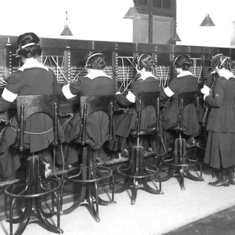 Women sit in a row and work at a telephone switchboard.