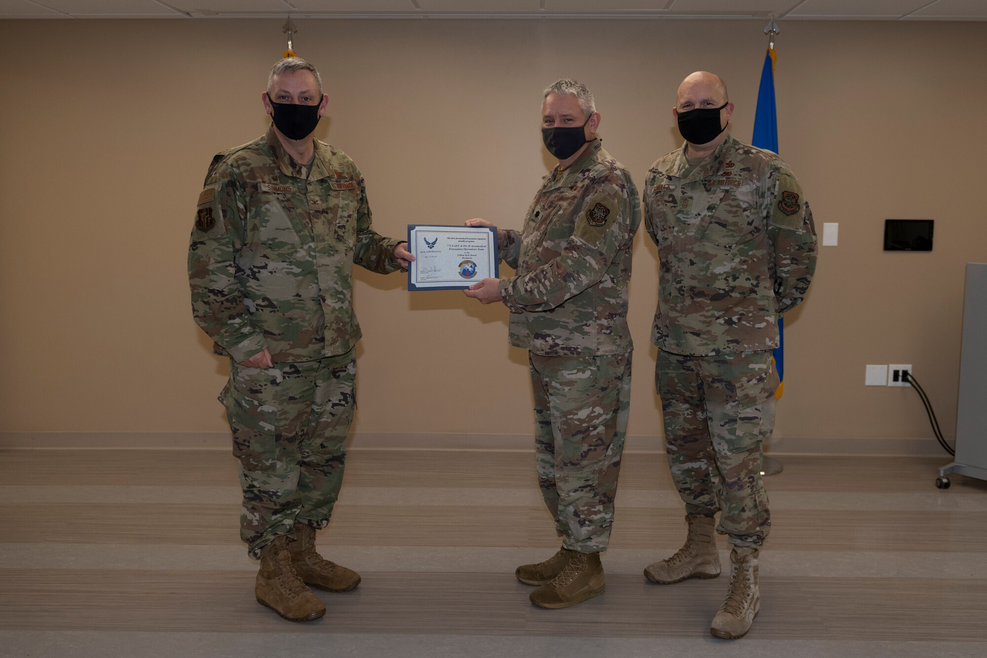 U.S. Air Force Col. Corey Simmons, left, 60th Air Mobility Wing commander, and Chief Master Sgt. Robert Schultz, right, 60th AMW command chief, award Lt. Col. Jerry Earl, 60th Aeromedical Evacuation Squadron director of readiness and training, with the Outstanding Mobility Airman Award during Leadership Rounds March 19, 2021, at Travis Air Force Base, California. The Leadership Rounds program provides 60th AMW leadership an opportunity to interact with Airmen and receive a detailed view of each mission performed at Travis AFB. (U.S. Air Force photo by Senior Airman Cameron Otte)