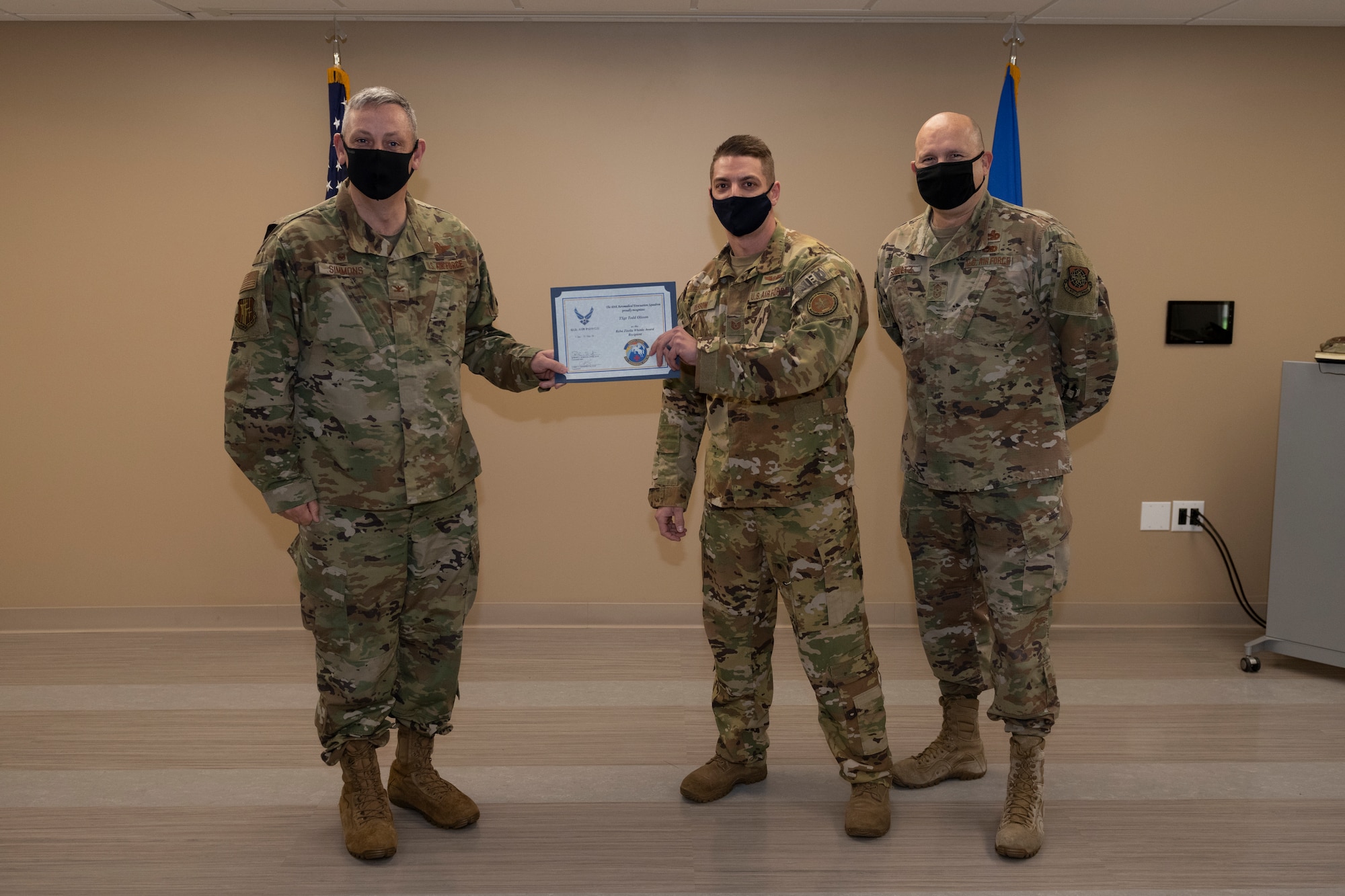 U.S. Air Force Col. Corey Simmons, left, 60th Air Mobility Wing commander, and Chief Master Sgt. Robert Schultz, right, 60th AMW command chief, award Tech. Sgt. Todd Olsson, 60th Aeromedical Evacuation Squadron noncommissioned officer in charge of standards and evaluations, with the Outstanding Mobility Airman Award during Leadership Rounds March 19, 2021, at Travis Air Force Base, California. The Leadership Rounds program provides 60th AMW leadership an opportunity to interact with Airmen and receive a detailed view of each mission performed at Travis AFB. (U.S. Air Force photo by Senior Airman Cameron Otte)