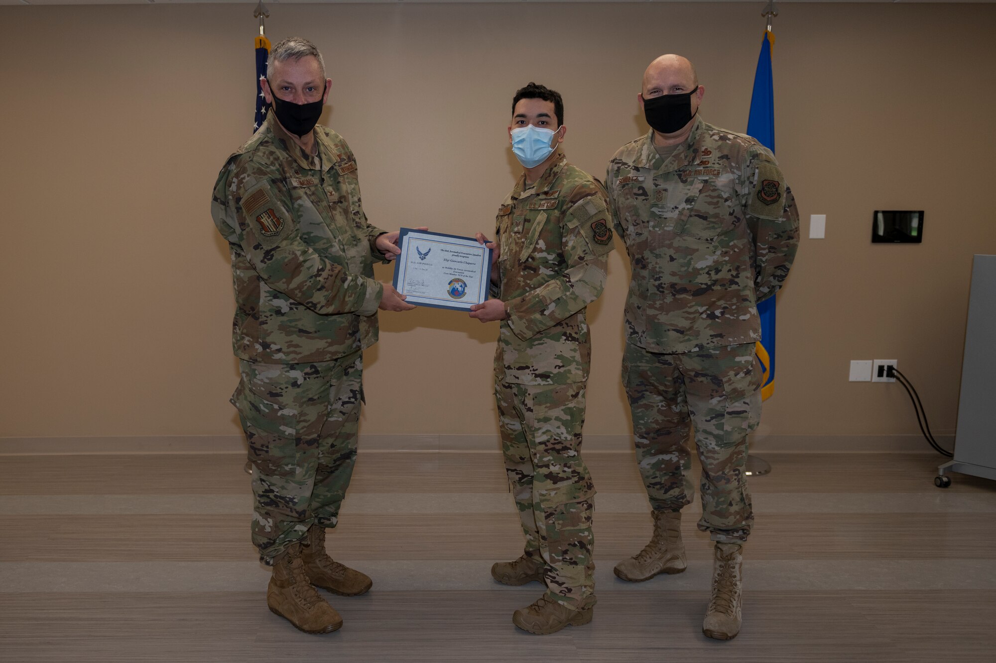 U.S. Air Force Col. Corey Simmons, left, 60th Air Mobility Wing commander, and Chief Master Sgt. Robert Schultz, right, 60th AMW command chief, award Staff Sgt. Giancarlo Chapparro, 60th Aeromedical Evacuation Squadron flight instructor, with the Outstanding Mobility Airman Award during Leadership Rounds March 19, 2021, at Travis Air Force Base, California. The Leadership Rounds program provides 60th AMW leadership an opportunity to interact with Airmen and receive a detailed view of each mission performed at Travis AFB. (U.S. Air Force photo by Senior Airman Cameron Otte)