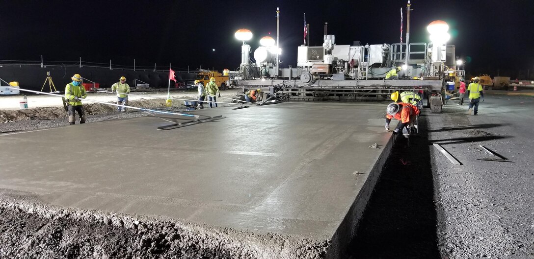 Sub-contractors for Kiewit smooth the cement surface of the new F-22 Fighter Alert Facility taxiway during a night paving Feb. 23 at Joint Base Pearl Harbor-Hickam.  During the five-hour-plus construction session the 40-ton crawler-type concrete finisher machine cast more than  360 cubic yards of Portland Cement Concrete Pavement (PCCP) for the taxiway.