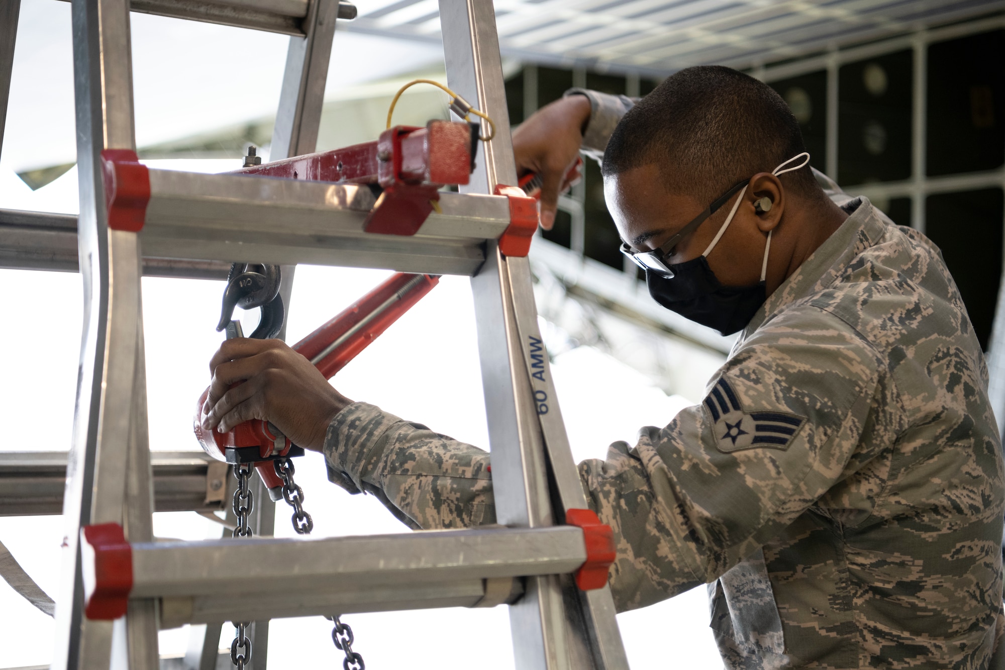 Senior Airman Saajaadeen Jeffries, 60th Aircraft Maintenance Squadron crew chief, lowers a cargo winch on a C-5M Super Galaxy March 18, 2021, at Travis Air Force Base, California. Travis Airmen collaborated with the Air Staff Logistics Directorate’s Tesseract team and key partners from the C-5 program office to implement commercial maintenance practices in scheduling and completing maintenance around flying demands. (U.S. Air Force photo by Airman 1st Class Alexander Merchak)