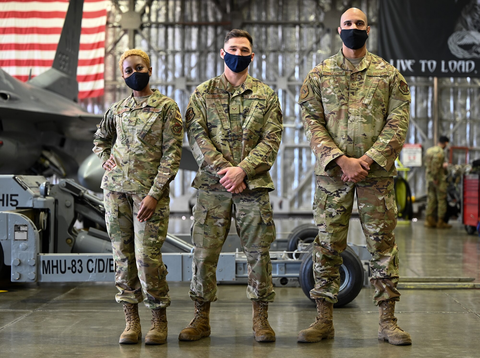 Senior Airmen JoAnn Morgan (left), Ryan Robins (center), both 13th Aircraft Maintenance Unit weapons load crew members, and Staff Sgt. Jonathan Gonzales, a 13th AMU weapons load crew chief, stand in front of the F-16 Fighting Falcon they’ll configure with munitions during the 4th quarter Load Competition at Misawa Air Base, Japan, Mar. 19, 2021.