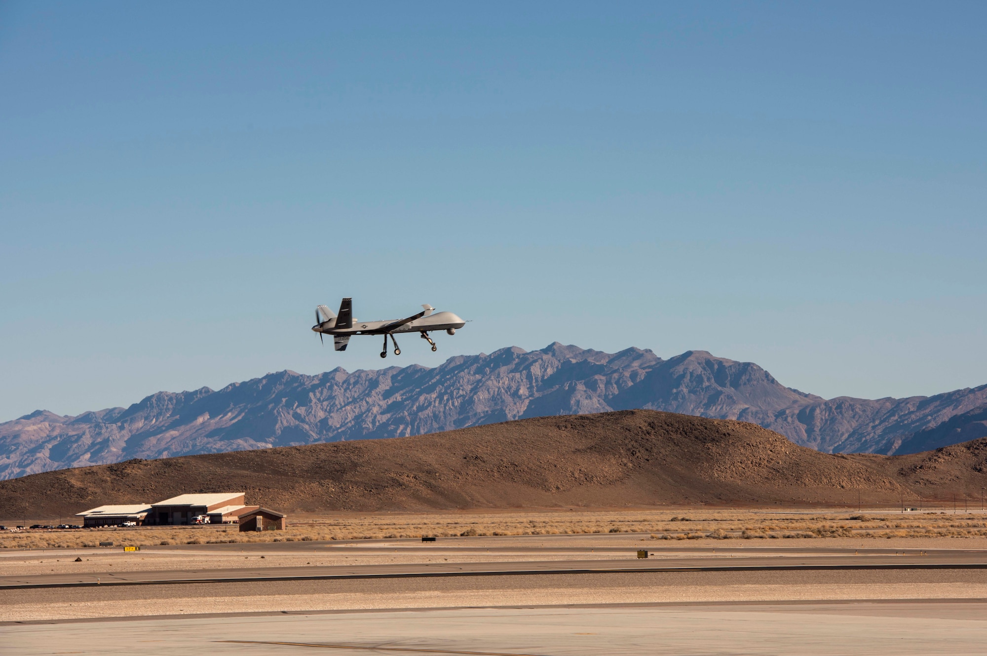 An MQ-9 Reaper flies over the base.
