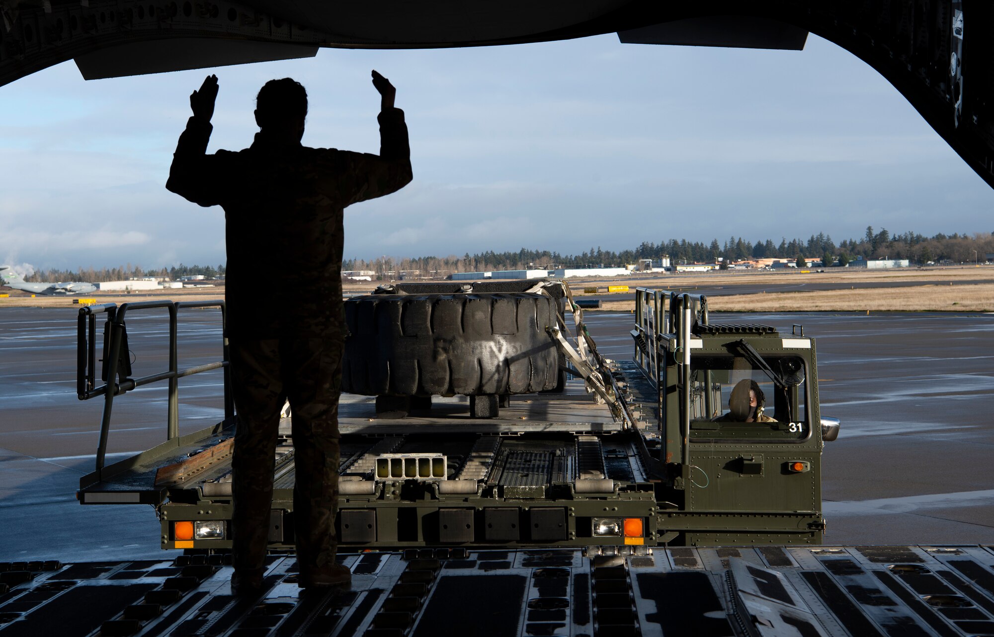 U.S. Air Force Tech. Sgt. Jaideep Kaur, 7th Airlift Squadron Operations flight chief, marshals a 62nd Aerial Port Squadron vehicle toward the ramp of a C-17 Globemaster III at Joint Base Lewis-McChord, Washington, Dec. 14, 2020. Kaur and other Team McChord Airmen participated in an all-female training mission to honor women in the Air Force. (U.S. Air Force photo by Senior Airman Tryphena Mayhugh)
