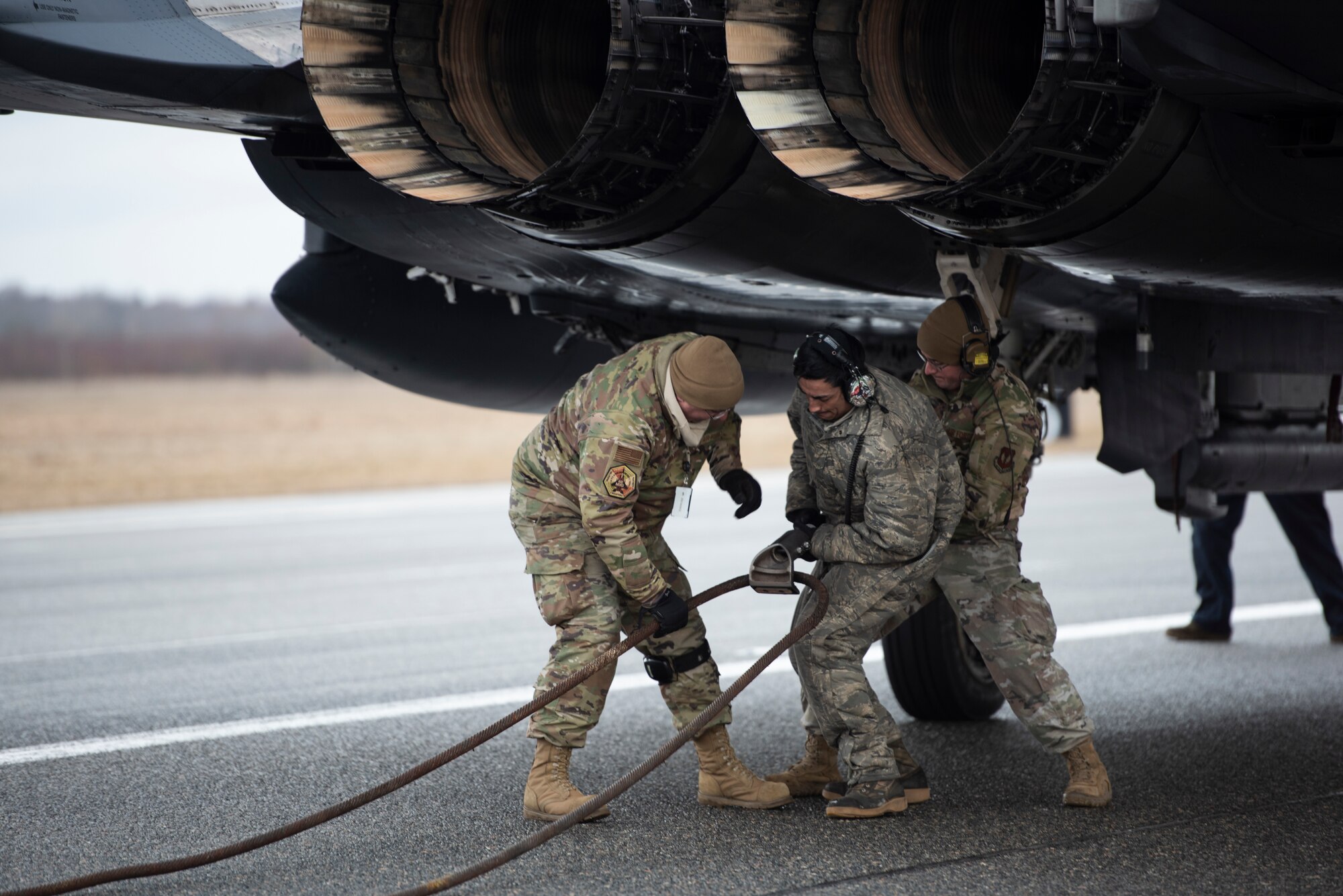 Airmen assigned to the 48th Aircraft Maintenance Squadron release the cable from the tailhook of a 492nd Fighter Squadron F-15E Strike Eagle during a Barrier Arresting Kit certification at Ämari Air Base, Estonia, March 17, 2021. During the test, the tailhook or arresting hook is dropped from the back of the F-15 as it fast taxis down the runway and catches the cable, which acts as a braking system to safely slow the aircraft during an emergency that would prevent the aircraft from performing a standard landing. (U.S. Air Force photo by Airman 1st Class Jessi Monte)