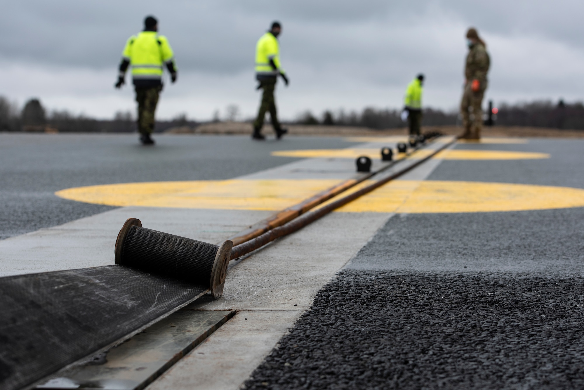 U.S. Air Force Airman 1st Class Chelsea Glasscock, 435th Construction and Training Squadron Aircraft Arresting System Depot apprentice, works with Ämari Air Base personnel to return the system to its starting position during a Barrier Arresting Kit certification at Ämari AB, Estonia, March 17, 2021. An aircraft arresting system is in place to bring aircraft to a safe stop in the event of an emergency that would prevent the aircraft from performing a standard landing. (U.S. Air Force photo by Airman 1st Class Jessi Monte)