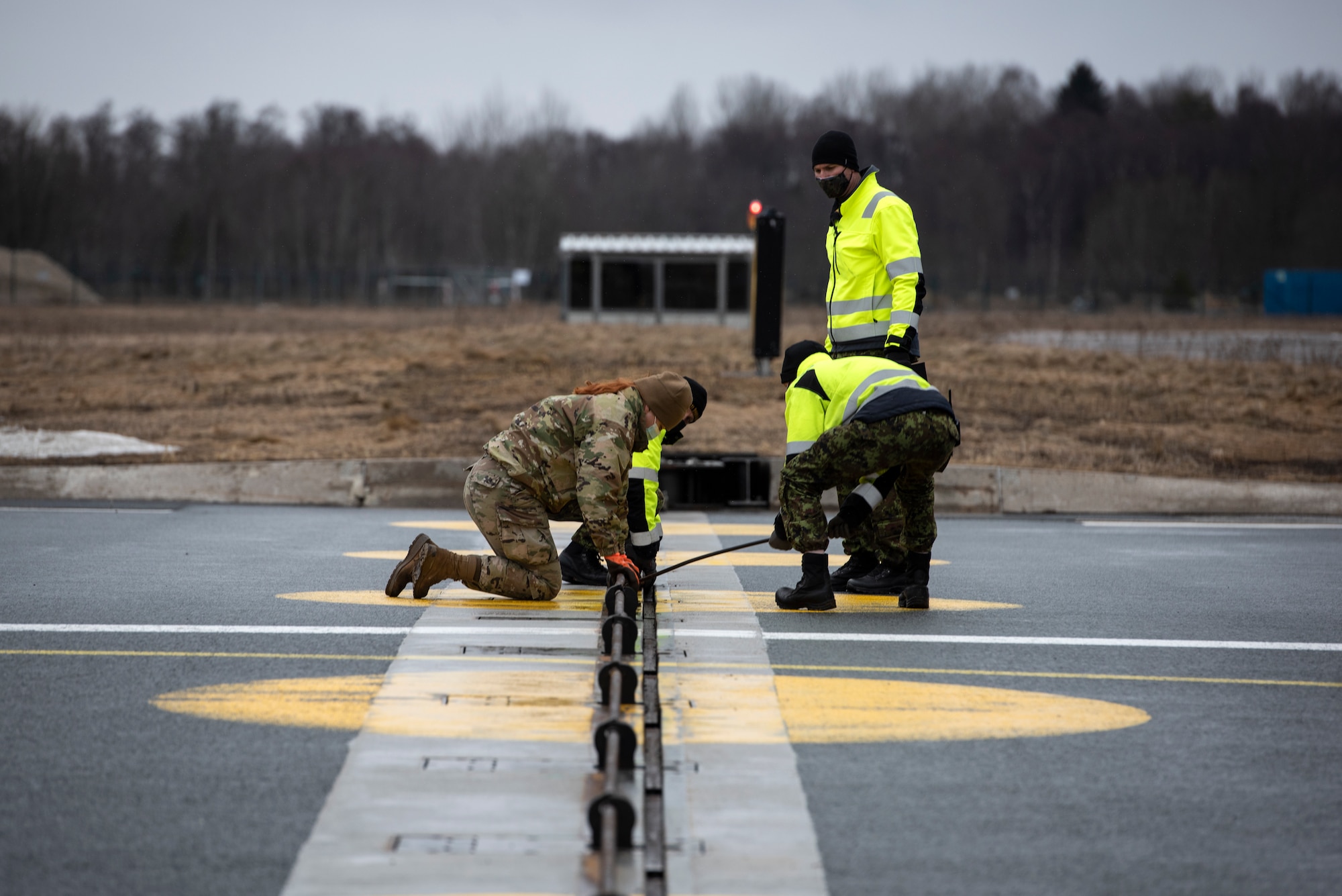 U.S. Air Force Airman 1st Class Chelsea Glasscock, 435th Construction and Training Squadron Aircraft Arresting System Depot apprentice, works with Ämari Air Base personnel to return the system to its starting position during a Barrier Arresting Kit certification at Ämari AB, Estonia, March 17, 2021. The BAK is certified annually to test the stability and effectiveness of the system, which acts as a braking mechanism to stop the aircraft in the event of an emergency that would prevent the aircraft from performing a standard landing. (U.S. Air Force photo by Airman 1st Class Jessi Monte)