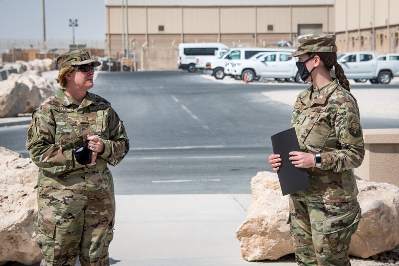 an airman receives a certificate from her supervisor in a ceremony held outside