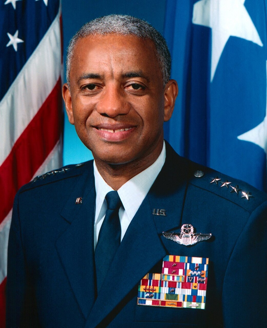 An Air Force general in uniform poses for a photo in front of the U.S. flag.
