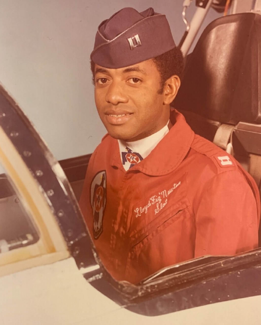 A man in a military uniform poses for a photo in the cockpit of an airplane.