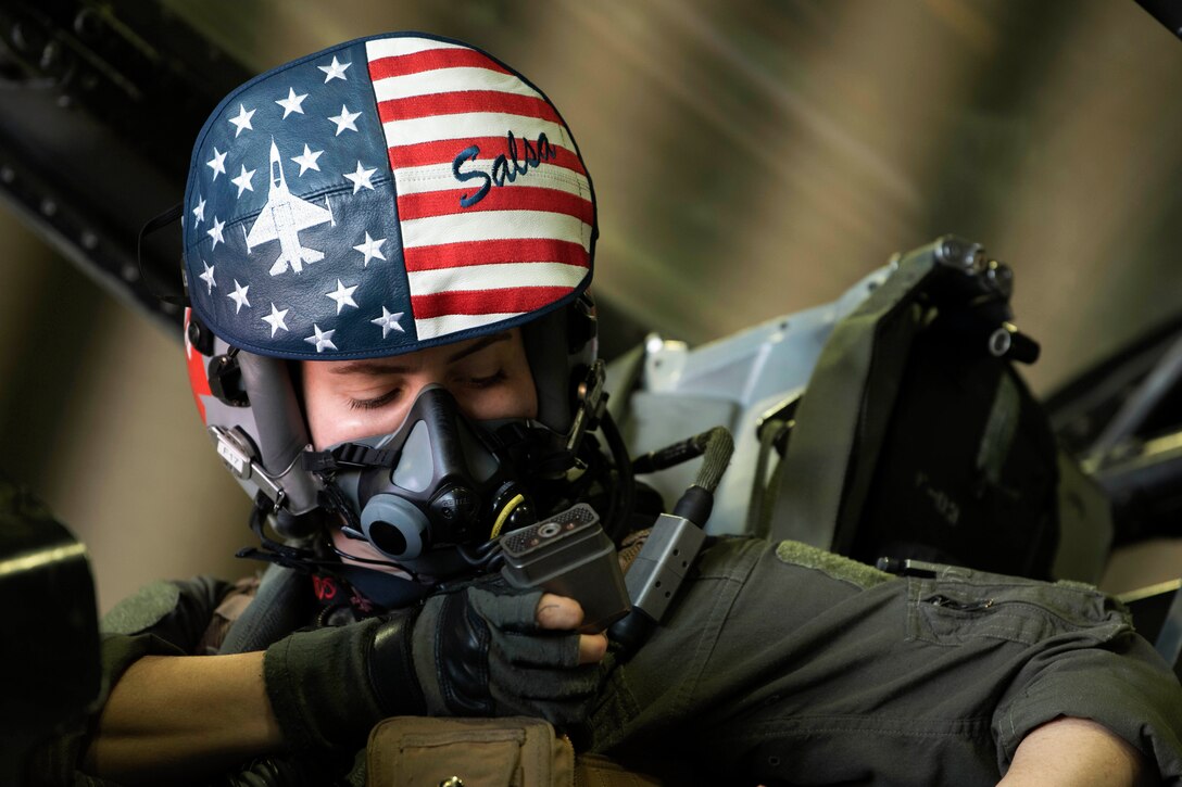 An airman prepares for flight while sitting in the cockpit of an aircraft.