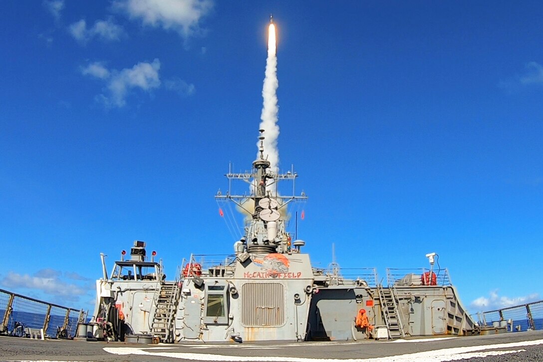 A missile launches from a ship at sea.