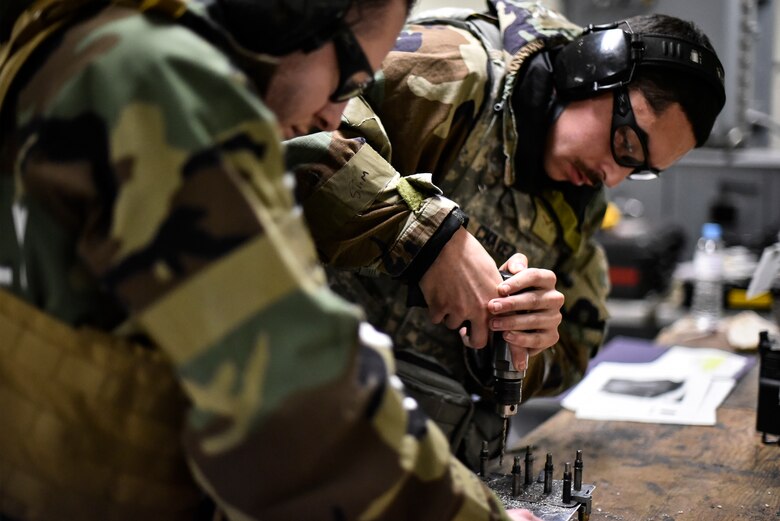 Airmen use tools to repair an aircraft component.