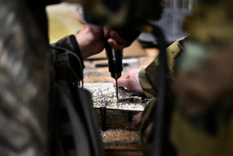 Airmen use tools to repair an aircraft component.