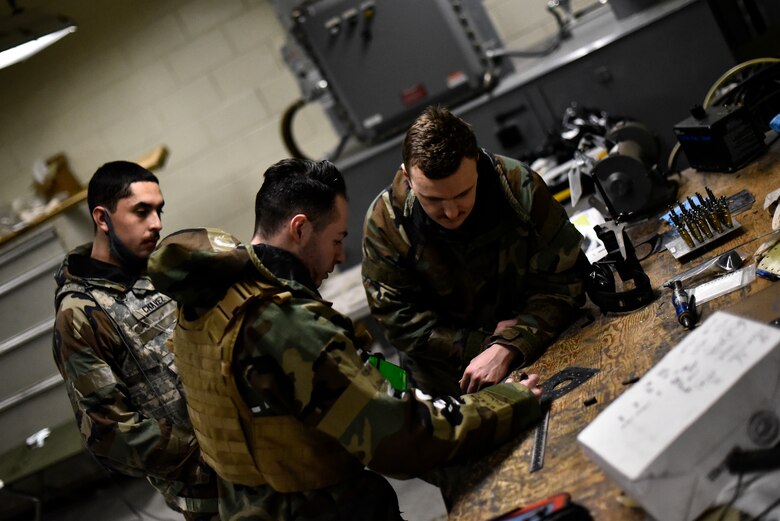 Airmen use tools to repair an aircraft component.