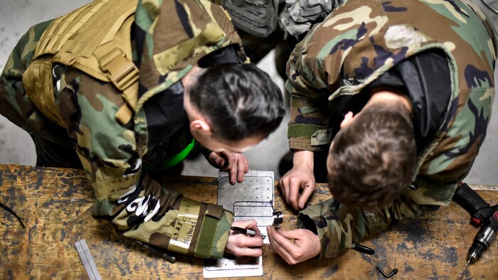 Airmen use tools to repair an aircraft component.