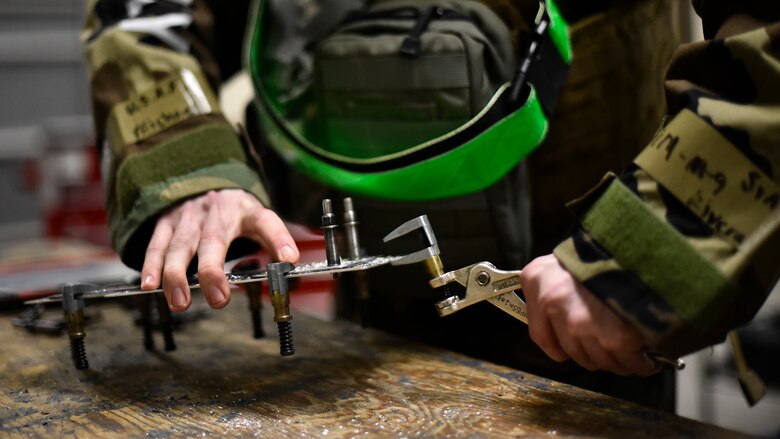 Airmen use tools to repair an aircraft component.