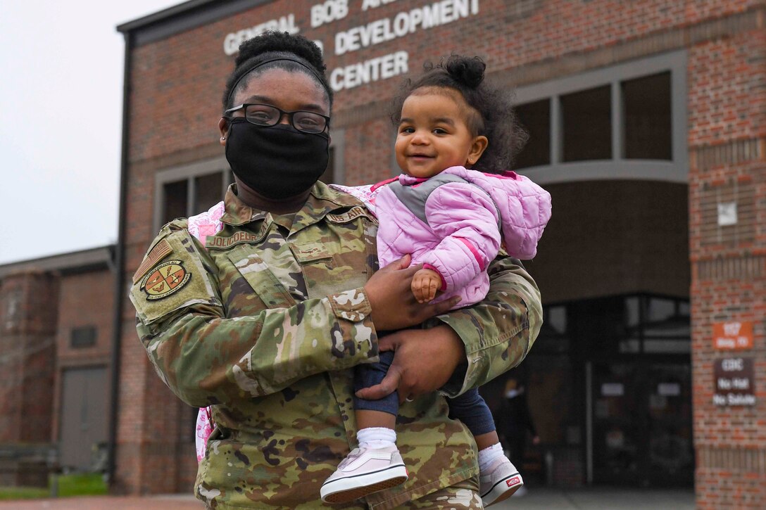 An airman carries a young child.