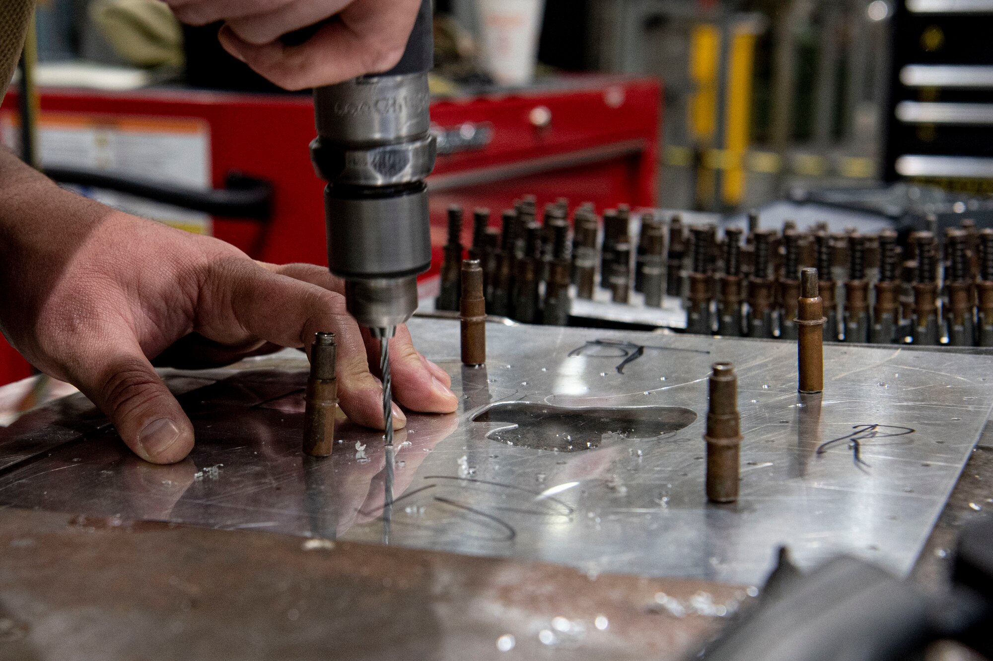 Photo of an Airman drilling holes into a sheet metal patch.