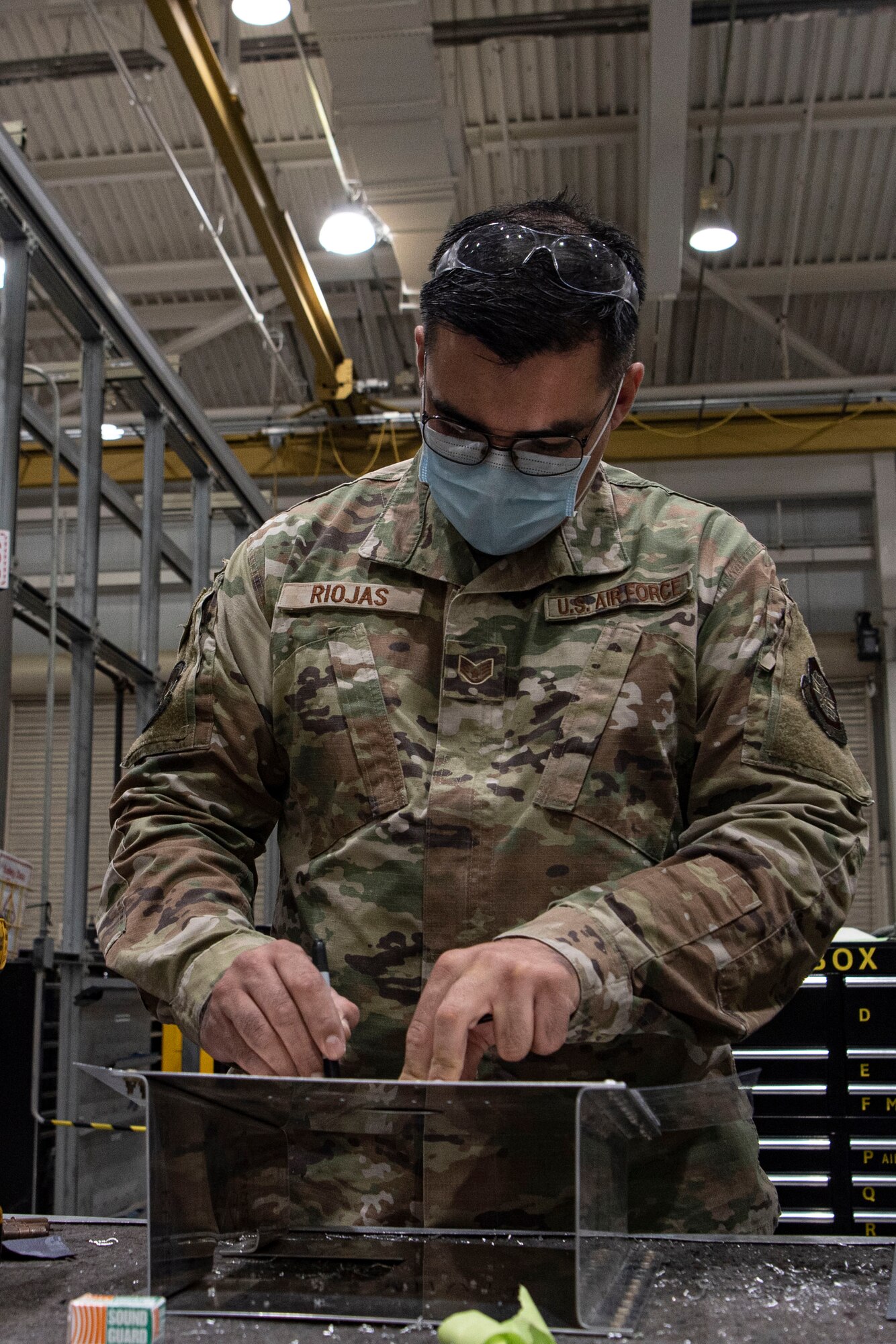 Photo of an Airman preparing a sheet metal patch.