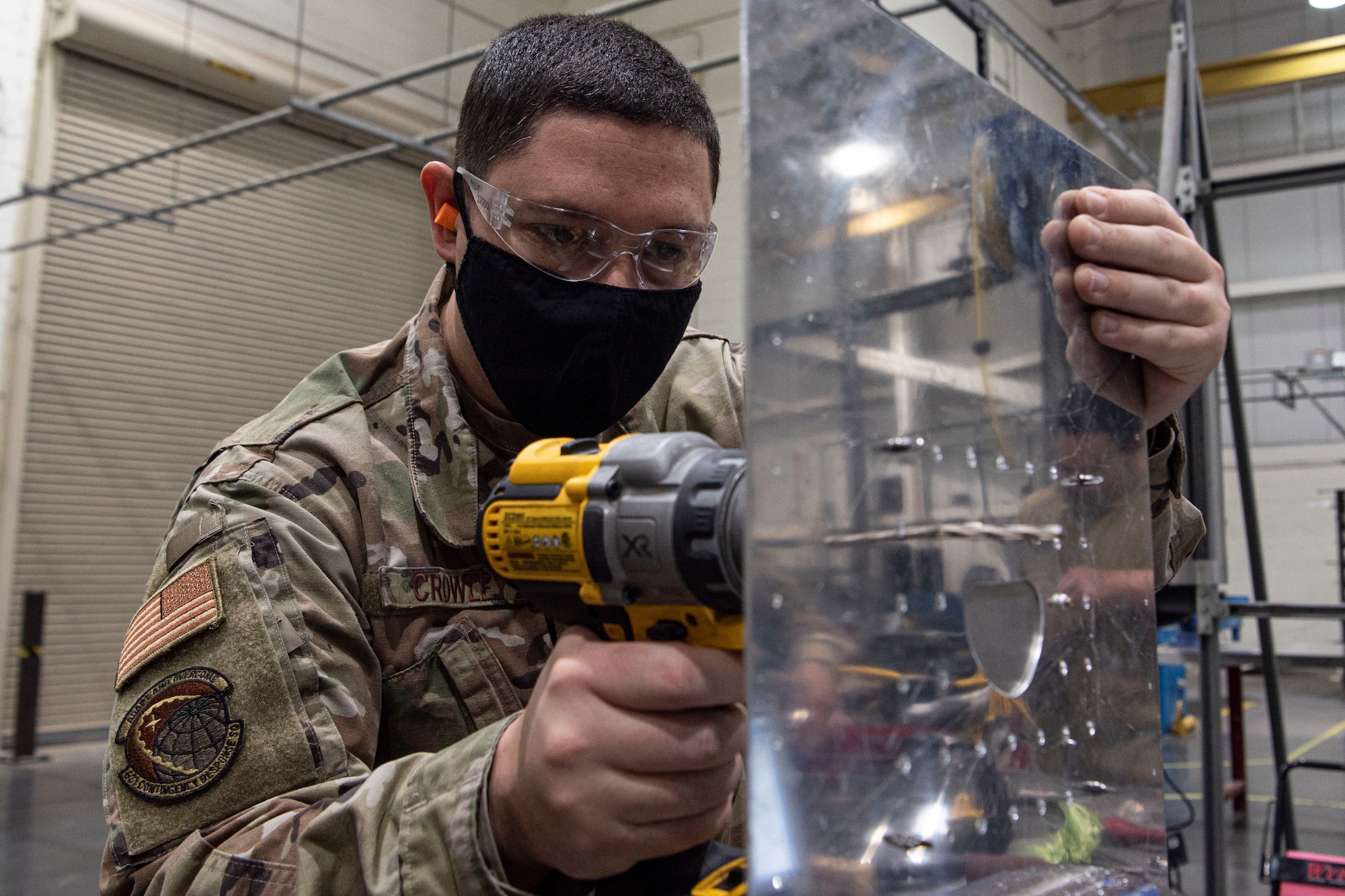 Photo of an Airman drilling holes into a sheet metal patch.