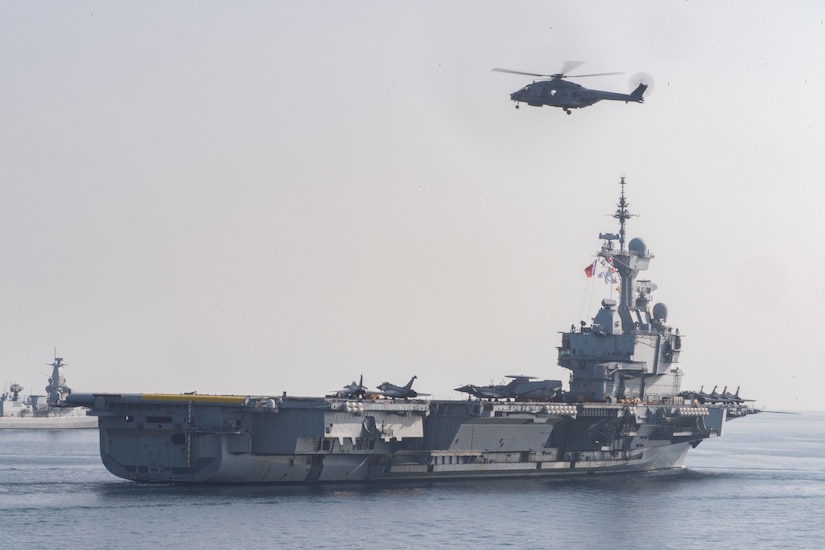 A helicopter flies over the French aircraft carrier Charles De Gaulle.