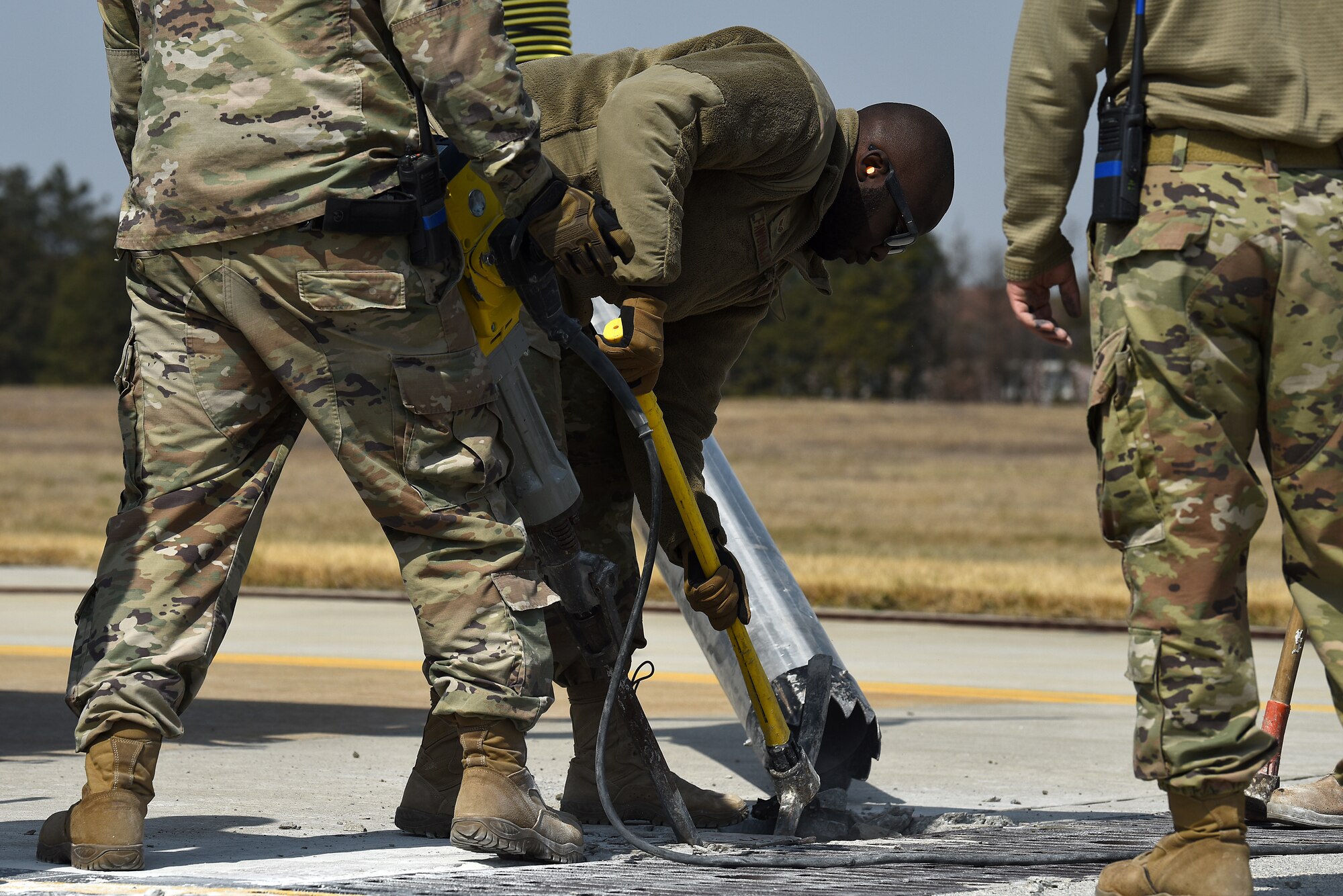 Senior Airman Manjel Faworaja, 8th Civil Engineer Squadron pavements and heavy equipment operator, uses a pick to break failed concrete on a taxiway at Kunsan Air Base, Republic of Korea, March 23, 2021. Pavements and heavy equipment operators are able to construct runways and airfields in remote global locations. (U.S. Air Force photo by Senior Airman Suzie Plotnikov)
